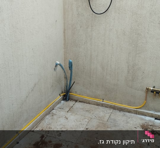 צינור גז צהוב מחובר לשסתום על קיר בטון